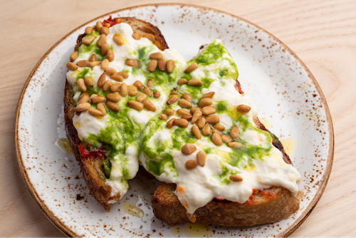Savory stracciatella and pesto on toast with pine nuts